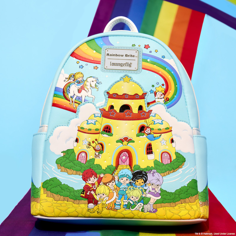 Loungefly Rainbow Brite Color Castle Mini Backpack sitting on a rainbow against a blue background. The bag features the Color Castle from Rainbow Brite, along with a rainbow behind it and the Color Kids. 